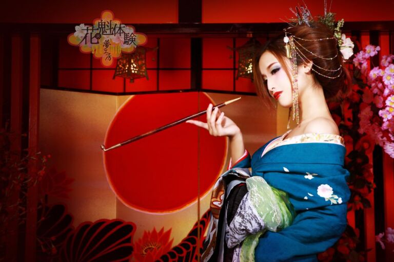 A woman in a blue kimono holds a long pipe against a red background with flowers and lanterns, evoking a geisha-like aesthetic.